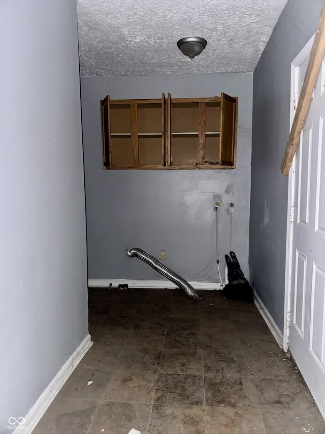 laundry area with laundry area, baseboards, and a textured ceiling