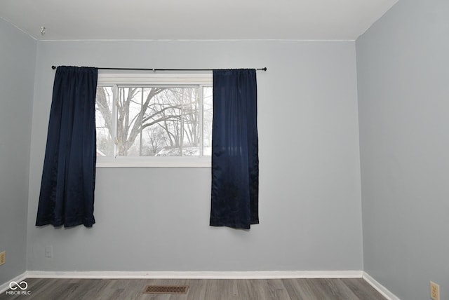 unfurnished room with baseboards, visible vents, and wood finished floors