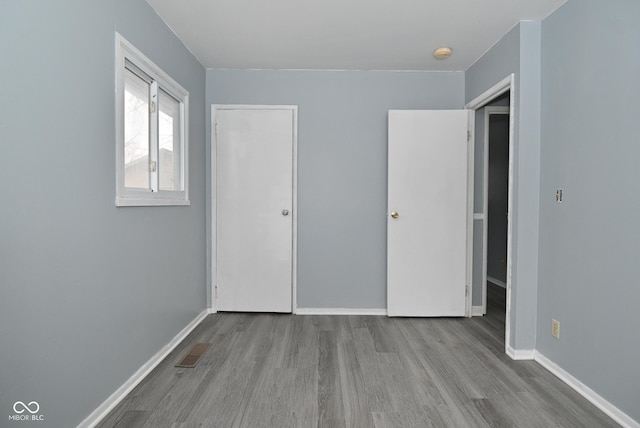 unfurnished bedroom with baseboards, visible vents, and wood finished floors