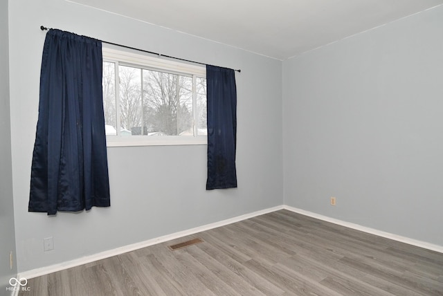 unfurnished room with visible vents, baseboards, and wood finished floors