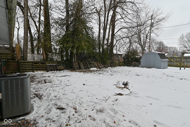 yard covered in snow featuring a storage unit and central air condition unit