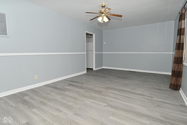 empty room with ceiling fan, wood finished floors, visible vents, and baseboards