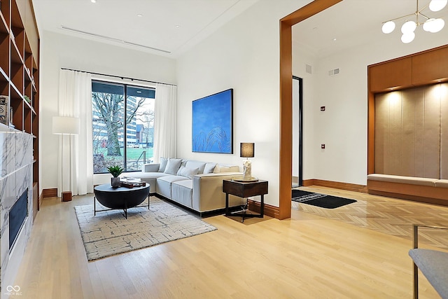 living room with a chandelier, elevator, a tile fireplace, and light hardwood / wood-style flooring