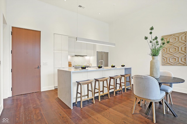 kitchen featuring white cabinets, a towering ceiling, dark hardwood / wood-style flooring, and high end fridge