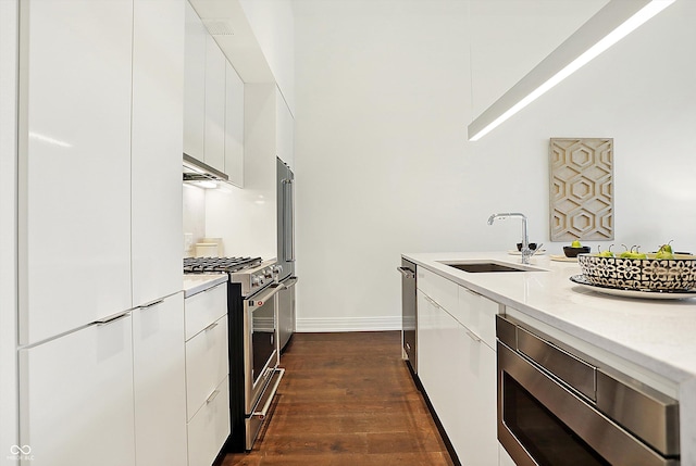 kitchen with white cabinets, premium appliances, dark hardwood / wood-style flooring, and sink