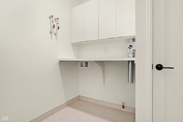 laundry area featuring hookup for a washing machine, light tile patterned flooring, and cabinets