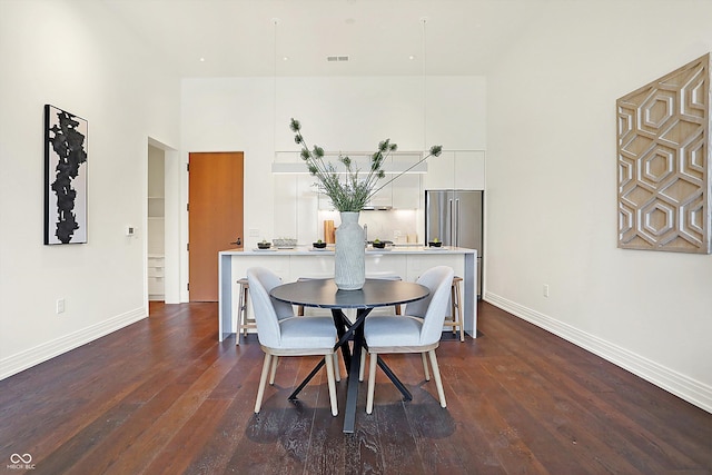 dining space featuring dark wood-type flooring and a high ceiling