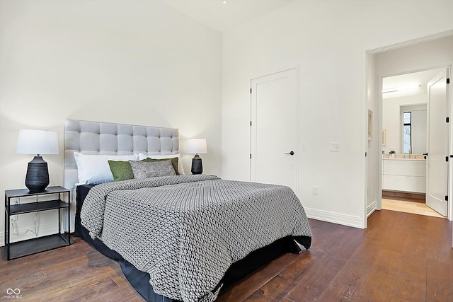 bedroom with ensuite bathroom and dark wood-type flooring