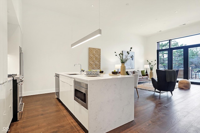 kitchen with white cabinetry, a kitchen island with sink, dark wood-type flooring, and appliances with stainless steel finishes