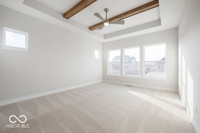 unfurnished room with a wealth of natural light, beamed ceiling, ceiling fan, and light colored carpet