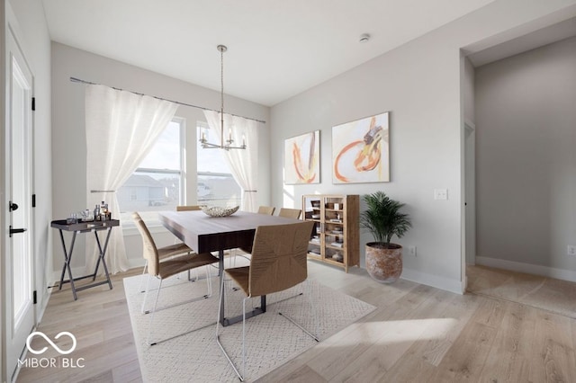 dining space with light hardwood / wood-style floors and a chandelier