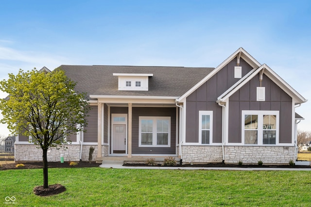 view of front facade with stone siding, board and batten siding, a front lawn, and a shingled roof