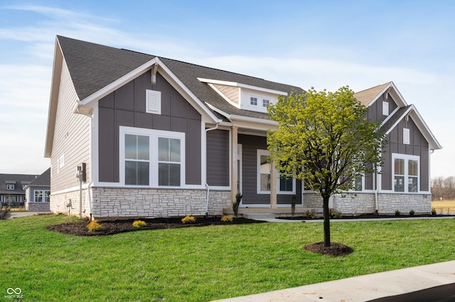 view of front of home with a front yard, board and batten siding, stone siding, and roof with shingles