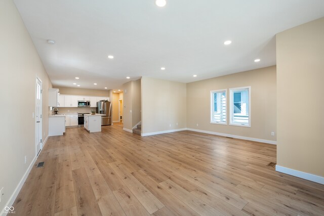 unfurnished living room featuring light hardwood / wood-style floors and sink