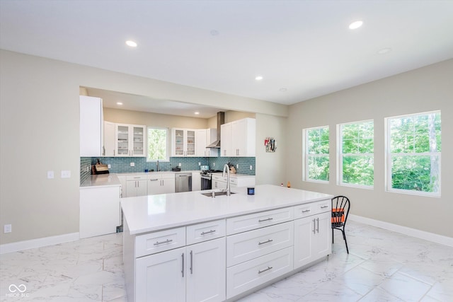 kitchen featuring white cabinetry, sink, backsplash, and an island with sink