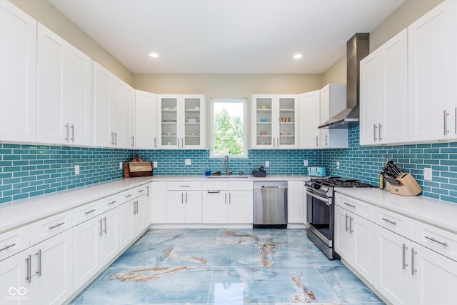 kitchen with white cabinets, stainless steel appliances, sink, and wall chimney exhaust hood