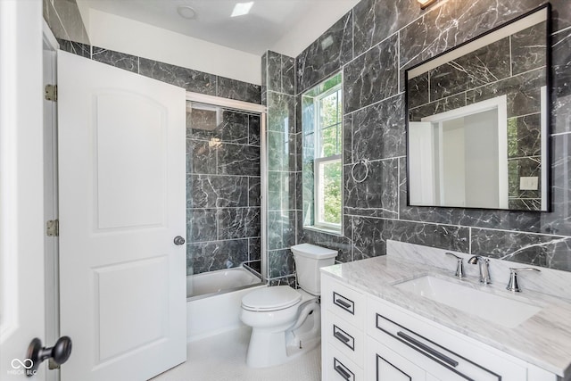 full bathroom featuring tile walls, vanity, toilet, tile patterned floors, and washtub / shower combination