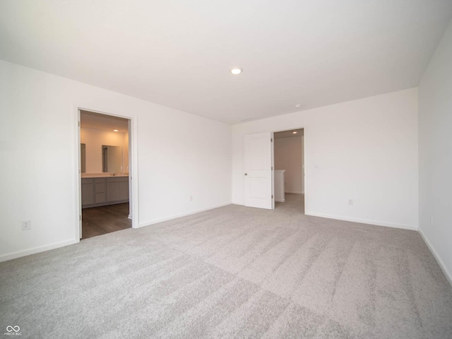 unfurnished bedroom with ensuite bathroom, carpet flooring, and a spacious closet