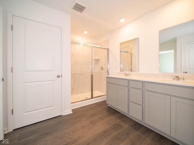 bathroom with wood-type flooring, a shower with shower door, and vanity