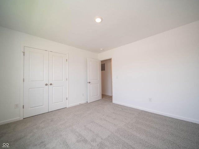 unfurnished bedroom with light carpet and a closet