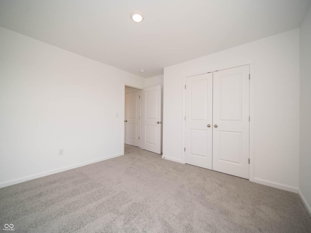 unfurnished bedroom with light colored carpet and a closet