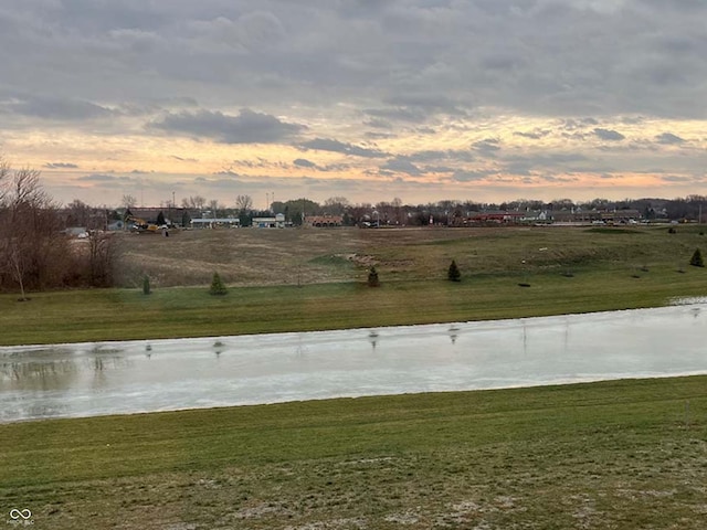 yard at dusk featuring a water view