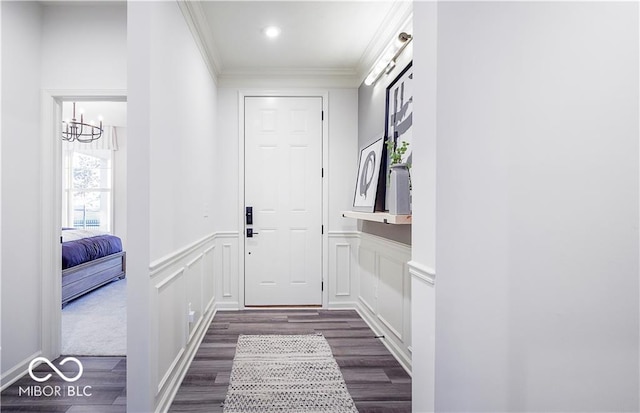 entryway featuring an inviting chandelier, dark wood-type flooring, crown molding, and a barn door