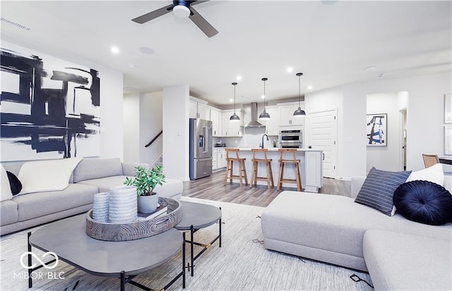 living room featuring sink, ceiling fan, and light hardwood / wood-style flooring