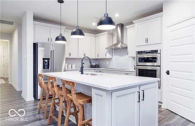 kitchen with stainless steel appliances, white cabinetry, sink, and wall chimney exhaust hood