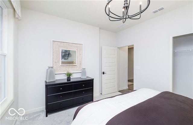 bedroom featuring an inviting chandelier, a closet, a spacious closet, and light carpet