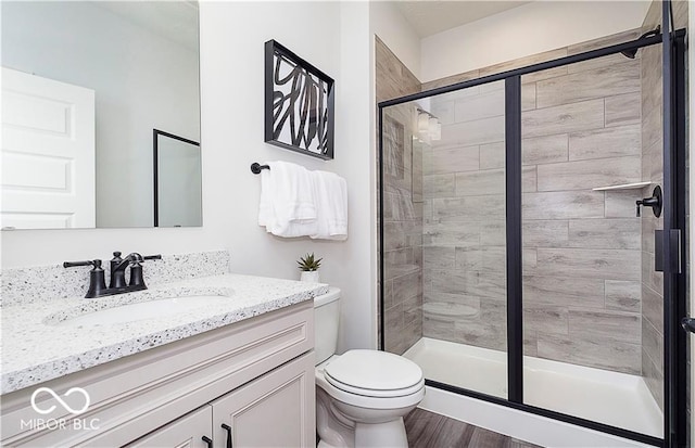 bathroom featuring toilet, an enclosed shower, vanity, and hardwood / wood-style floors