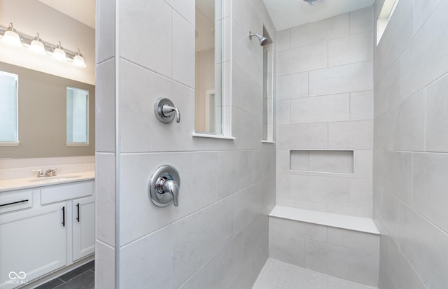 bathroom with tiled shower and vanity