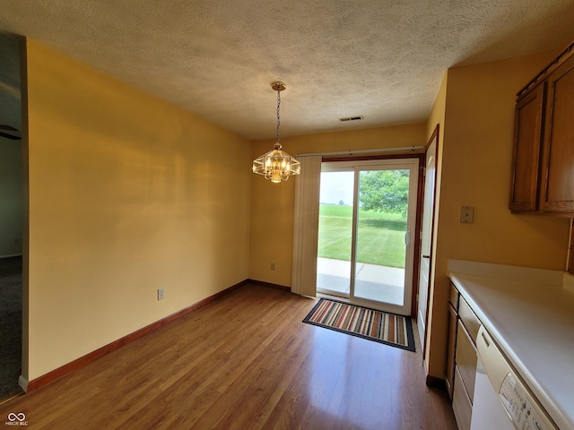 unfurnished dining area featuring a textured ceiling, light wood-type flooring, and an inviting chandelier