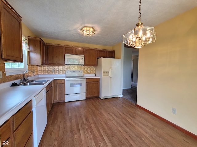 kitchen with hardwood / wood-style floors, white appliances, hanging light fixtures, decorative backsplash, and a textured ceiling