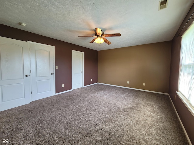 unfurnished bedroom featuring carpet flooring, a textured ceiling, and ceiling fan