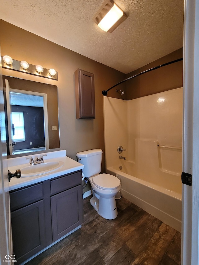 full bathroom with vanity, toilet, a textured ceiling, wood-type flooring, and tub / shower combination