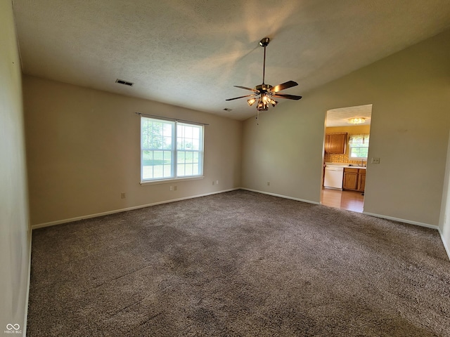 carpeted empty room with a textured ceiling, ceiling fan, lofted ceiling, and sink