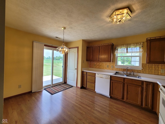 kitchen with backsplash, dishwasher, decorative light fixtures, and sink