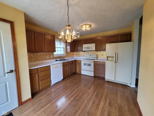 kitchen with light wood-type flooring, a textured ceiling, white appliances, a chandelier, and hanging light fixtures