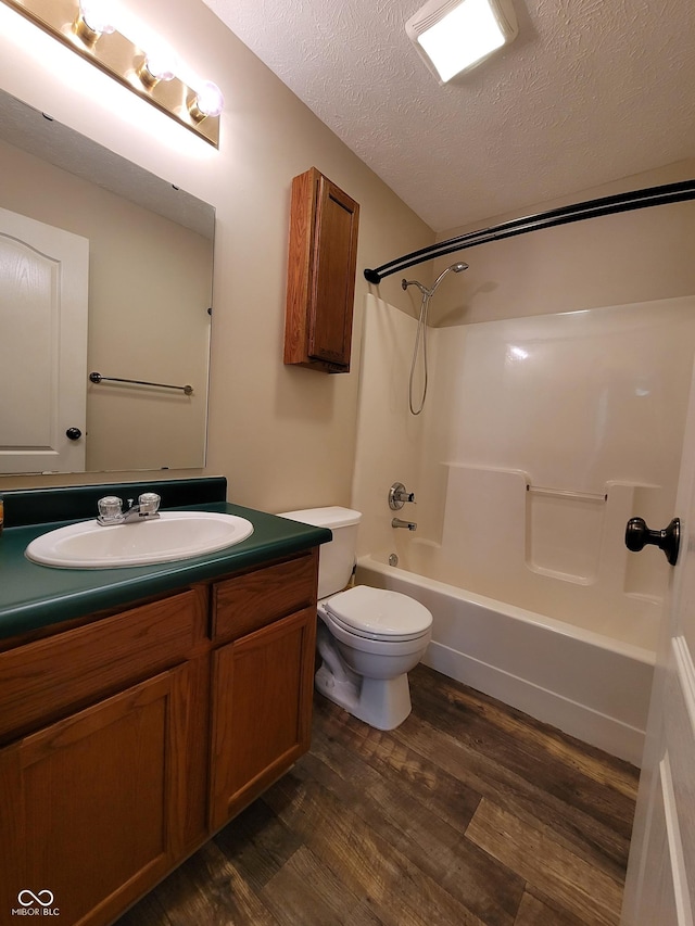 full bathroom with tub / shower combination, hardwood / wood-style floors, a textured ceiling, toilet, and vanity