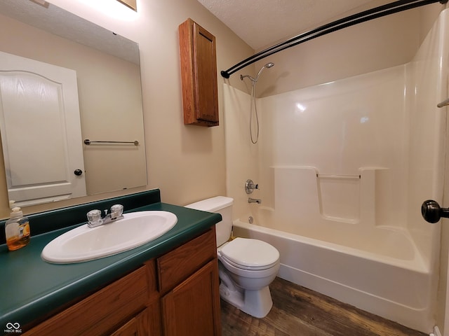 full bathroom with vanity, washtub / shower combination, hardwood / wood-style flooring, toilet, and a textured ceiling