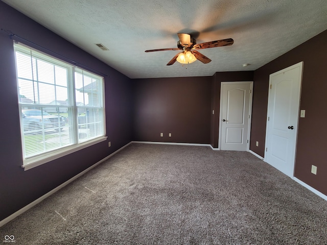 unfurnished room with carpet flooring, ceiling fan, and a textured ceiling