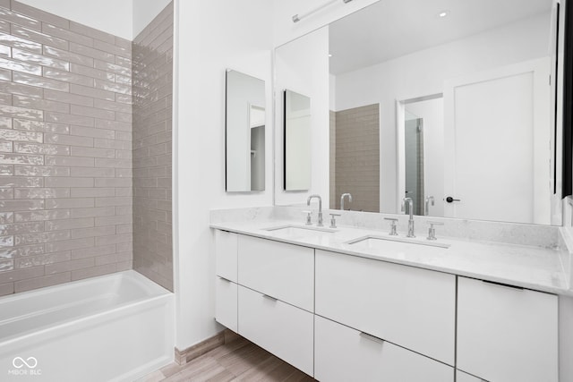 bathroom featuring hardwood / wood-style floors, vanity, and tiled shower / bath