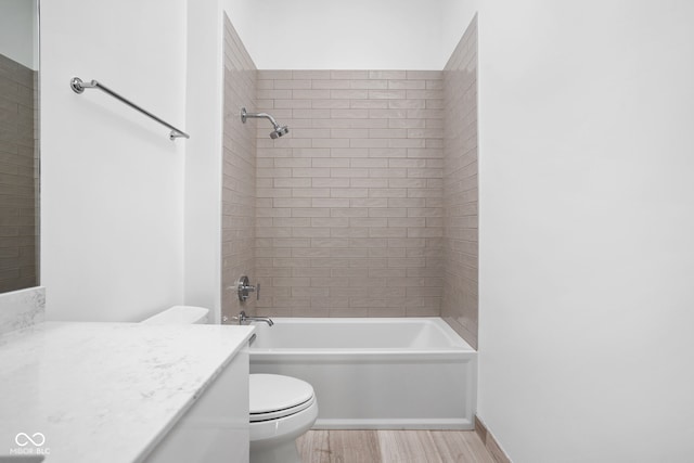 full bathroom with vanity, hardwood / wood-style flooring, toilet, and tiled shower / bath combo