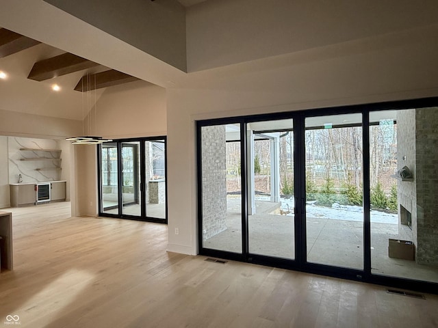 entryway featuring beamed ceiling, french doors, high vaulted ceiling, and light hardwood / wood-style flooring