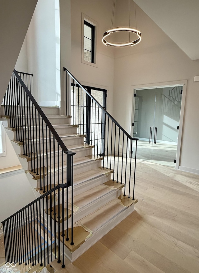 staircase featuring a towering ceiling and wood-type flooring