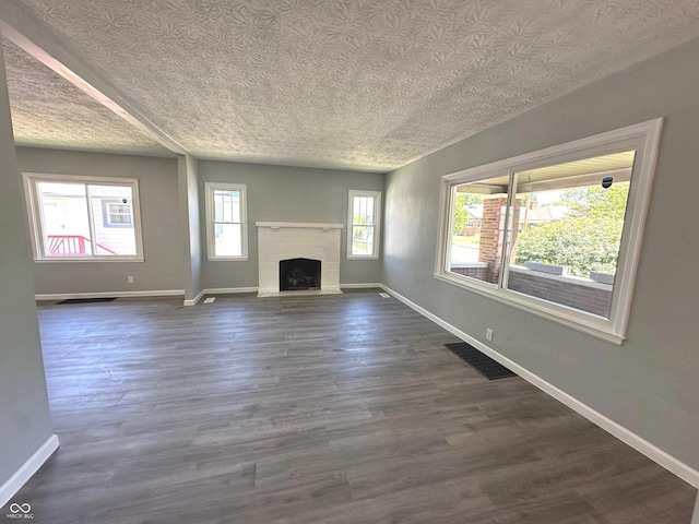 unfurnished living room with a textured ceiling and dark wood-type flooring