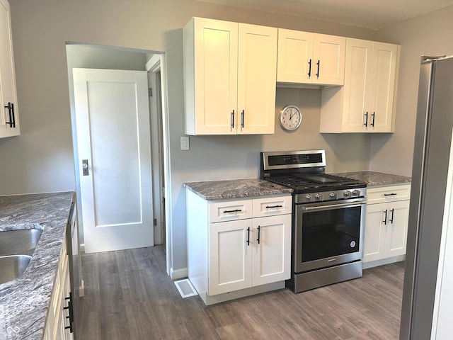 kitchen with white cabinets, stainless steel appliances, dark wood-type flooring, and dark stone countertops