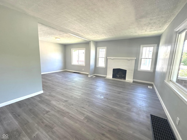 unfurnished living room with dark hardwood / wood-style flooring and a textured ceiling