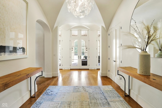 entryway with french doors, vaulted ceiling, a chandelier, and dark hardwood / wood-style flooring